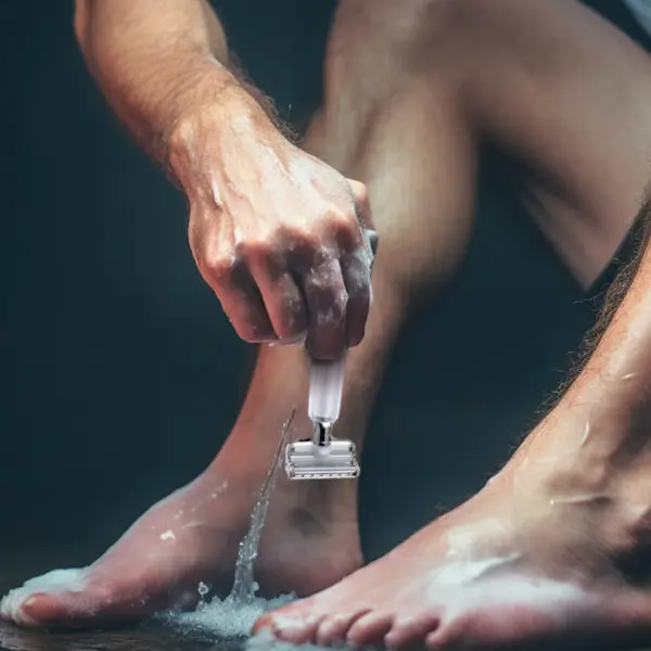 man shaving legs with safety razor